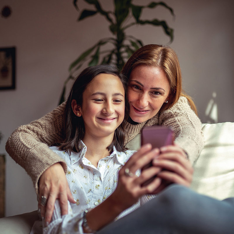 Two teenage girls looking at a phone and smiling.