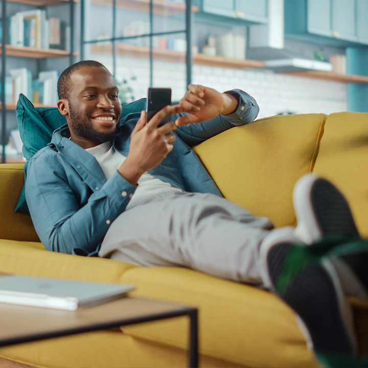 Men reclining on couch, feeling well supported by his digital banking tool